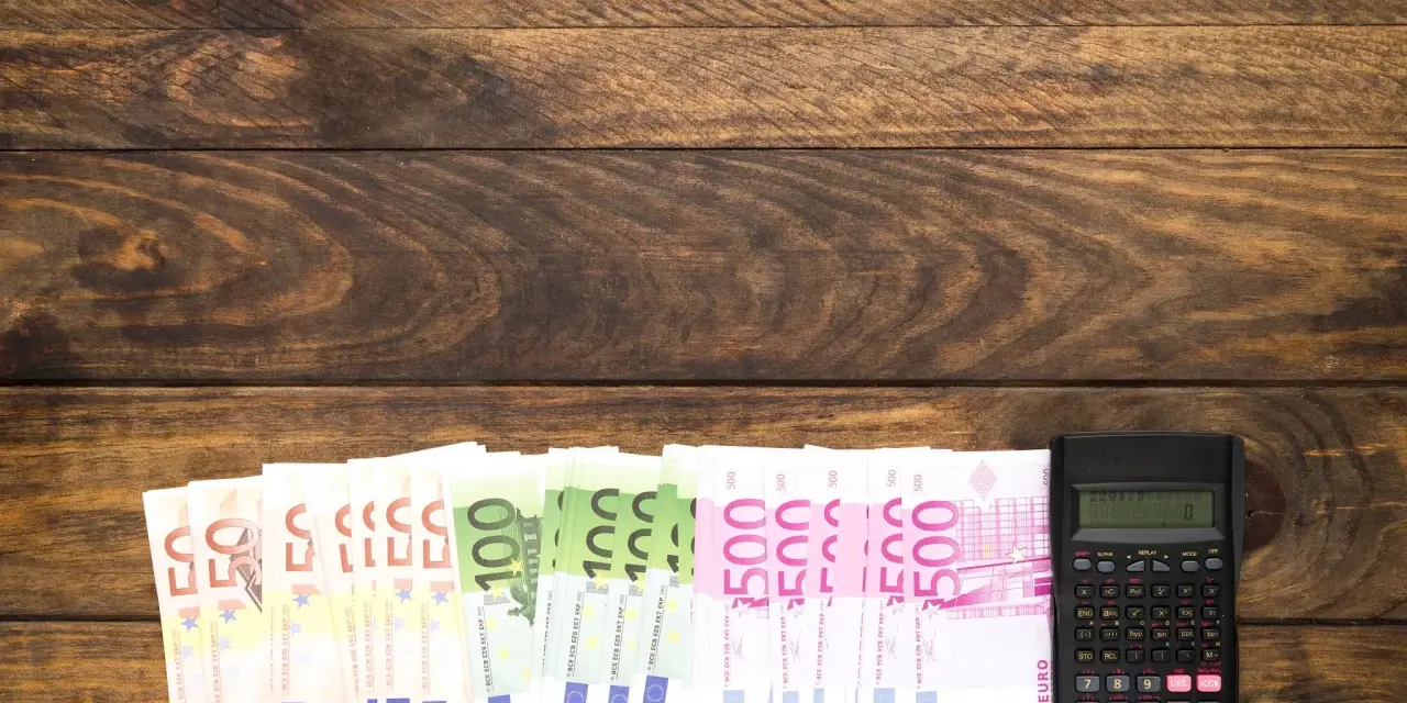 Banknoty euro i kalkulator na drewnianym tle.