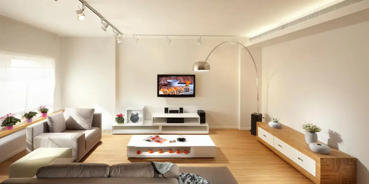 Iluminar un salón moderno con luces de riel y lámpara de arco. Sofás grises, mesa de centro blanca y mueble de TV.