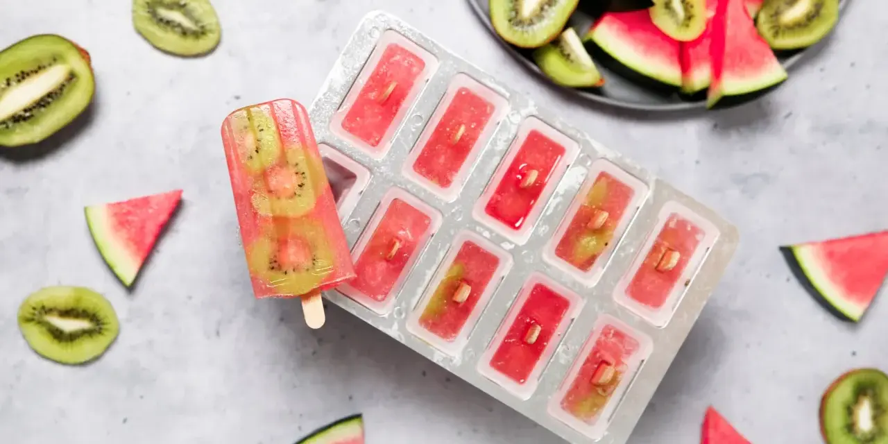 Erfrischendes Melonen-Kiwi-Eis in einer Form, daneben frische Früchte. Perfekt für heiße Tage!