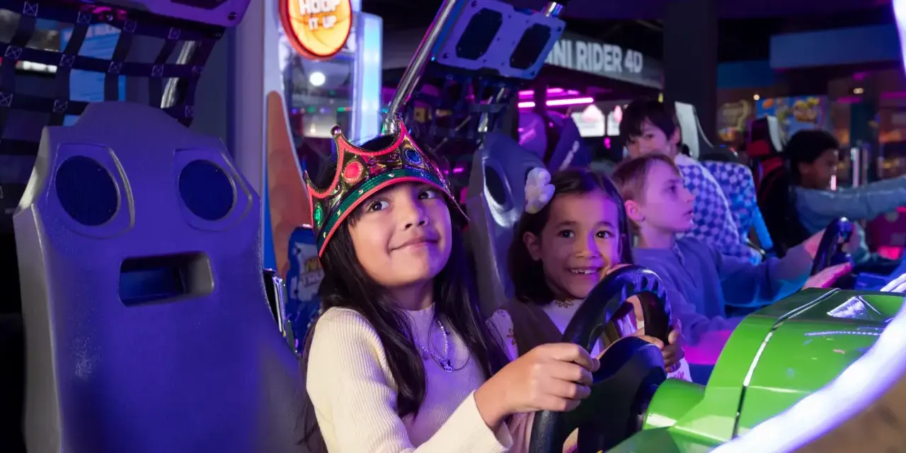 Kinder mit Kronen auf dem Kopf spielen in einer Spielhalle in Berlin Rennspiele.