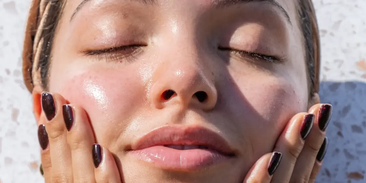 A woman's face, with eyes closed and skin glowing, touches her cheek. It makes you wonder, can your skin type change with the seasons?