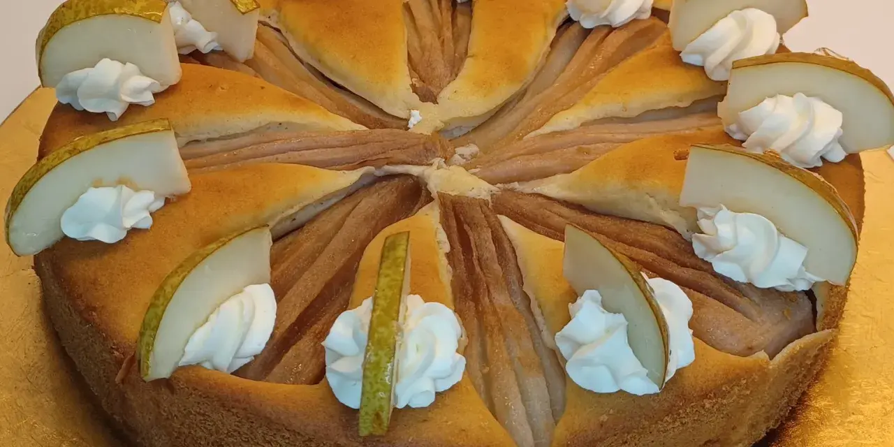 Ein köstlicher Birnenkuchen, verziert mit Sahnetupfern und frischen Birnenspalten. Perfekt für ein Birnenkuchen Rezept.