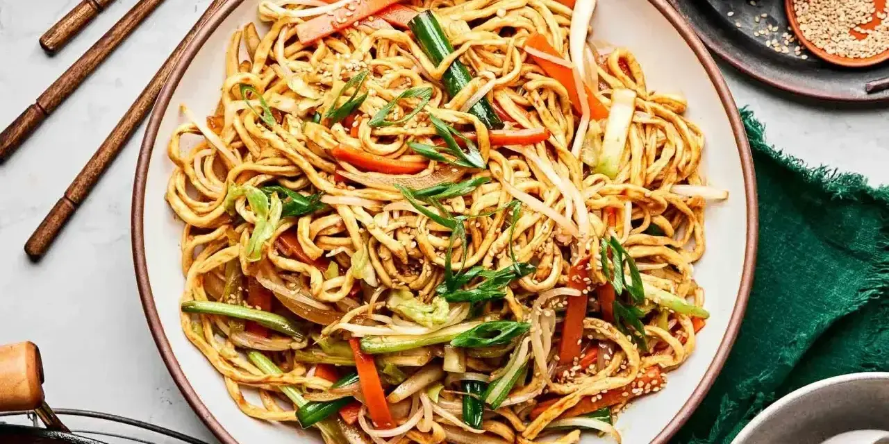 Pyszny makaron chow mein z warzywami i sezamem, gotowy do jedzenia pałeczkami.