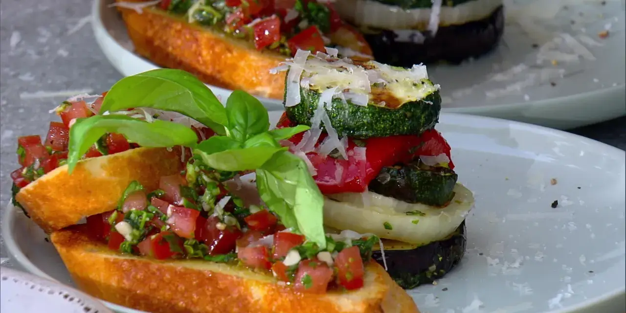 Vegane Grillrezepte: Bruschetta mit Tomaten und gegrilltem Gemüse-Turm, garniert mit Basilikum und Parmesan.