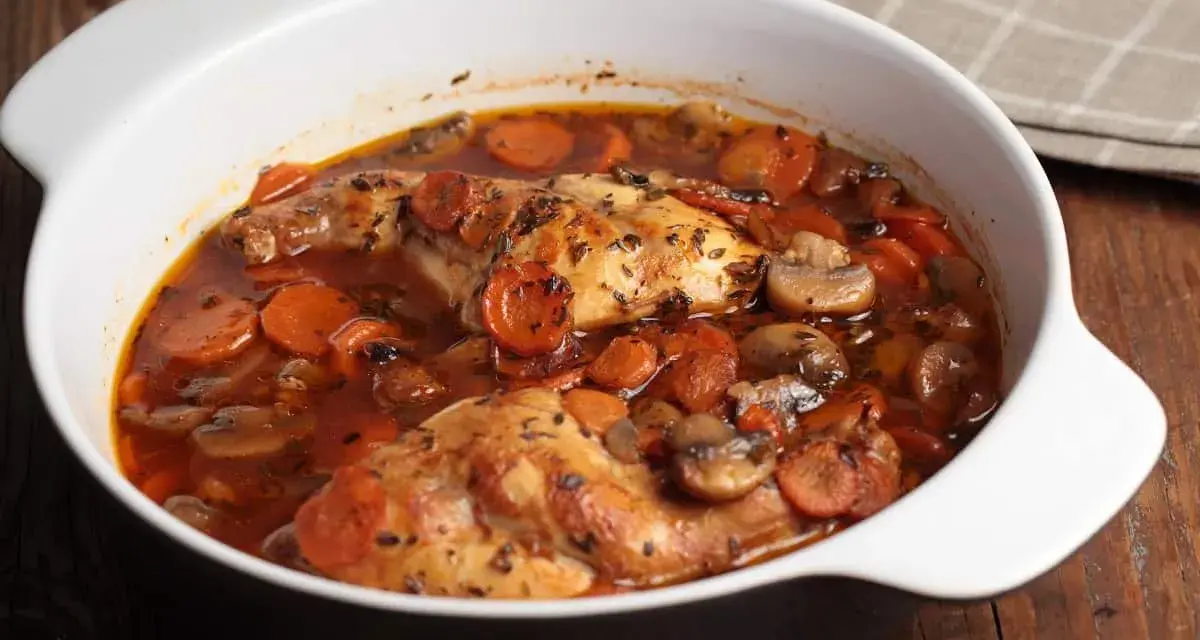 Conejo en cazuela con zanahorias y champiñones en salsa roja.