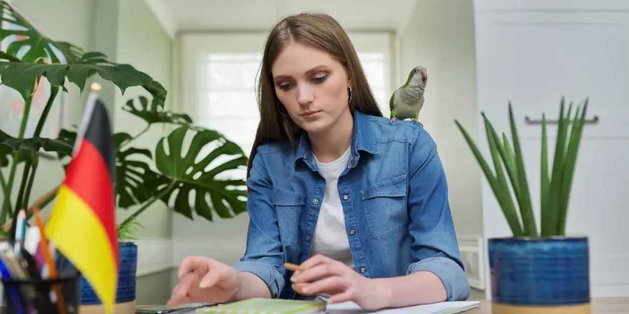 Dziewczyna z papugą na ramieniu uczy się niemieckiego. Może szuka inspiracji na piosenkę na urodziny po niemiecku?