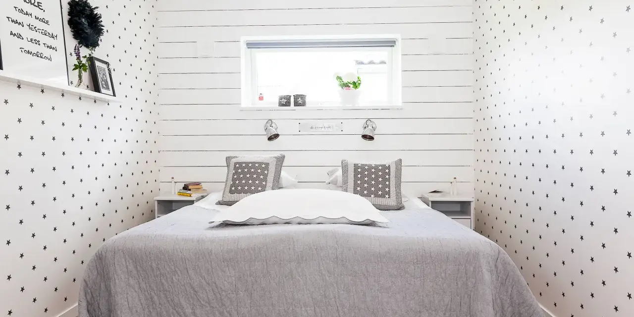 Ideen für ein sehr kleines Schlafzimmer einrichten: Sternen-Tapete, schlichtes Bett, Nachttische und ein Regal mit Deko.