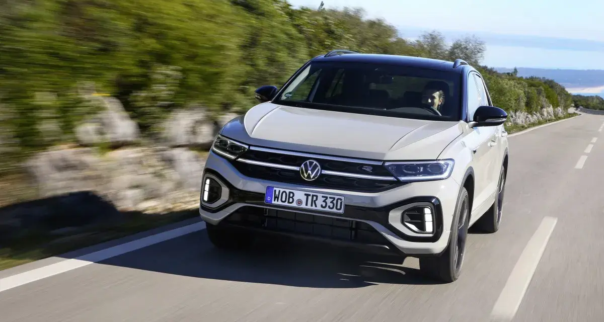 Jasnoszary Volkswagen T-Roc jedzie po krętej drodze. Nawet przy potencjalnych usterkach, ten model prezentuje się dynamicznie.