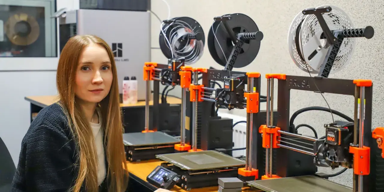 Kobieta w laboratorium obok rzędu drukarek 3D, które są kluczowe dla historii drukarki 3d.