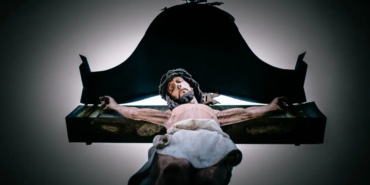 A statue of Jesus on the cross, with a dark canopy above. This image evokes the sacrifice and the question of why Jesus died.