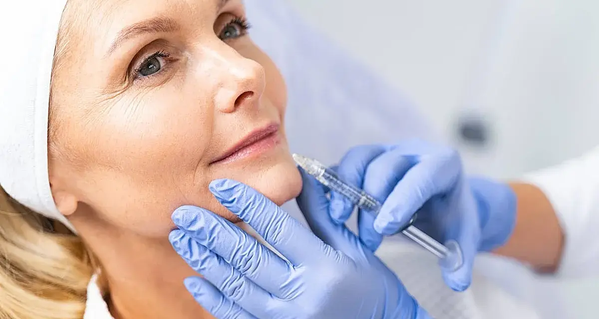 Mujer recibe tratamiento facial con exosomas. Manos enguantadas aplican inyección para rejuvenecer la piel.
