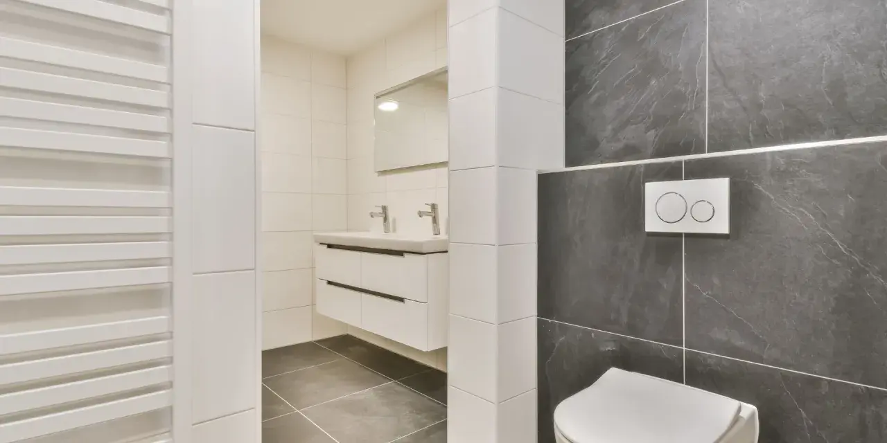 Salle de bain moderne avec wc suspendu, carrelage gris anthracite et blanc, lavabo suspendu et radiateur blanc.