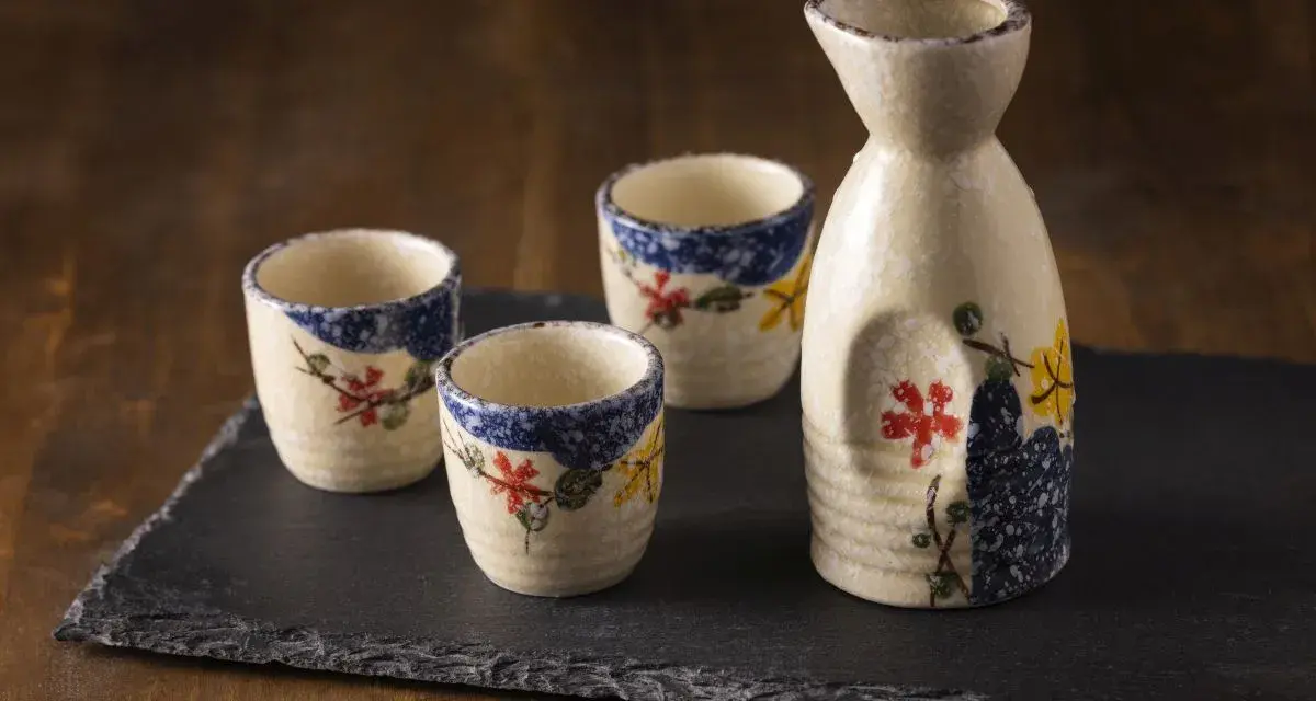 Zestaw do sake z ceramicznym dzbankiem i trzema kieliszkami, ozdobiony motywem kwiatowym. Idealny do degustacji sake, niezależnie od tego, sake ile procent ma zawartości alkoholu.