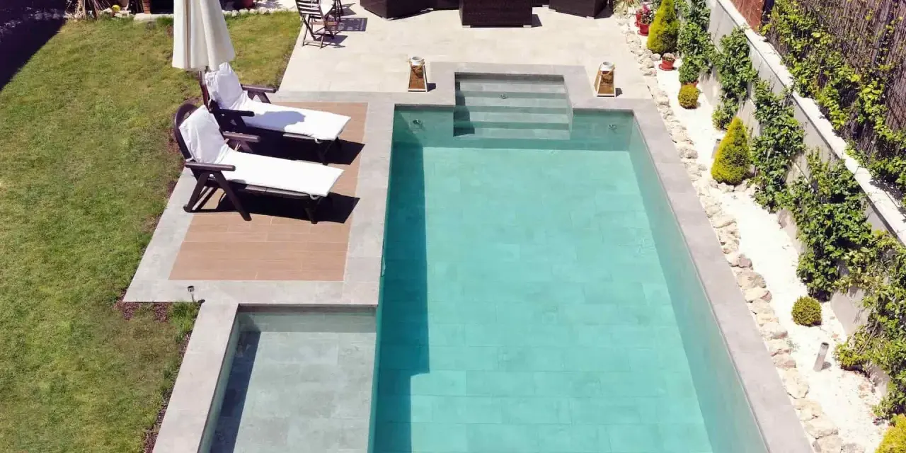 Un jardín con piscinas modernas, tumbonas, zona de estar y barbacoa.