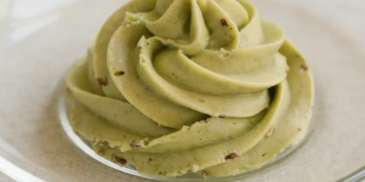 Puszysty krem pistacjowy do tortu, udekorowany na talerzyku.