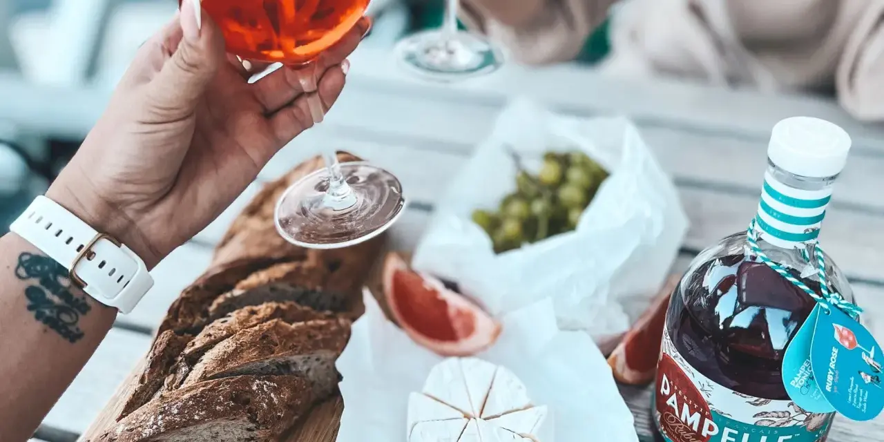Aperitif co to? Kieliszek Pamplelle Ruby Rose, bagietka, ser brie i winogrona tworzą idealny zestaw na letnie popołudnie.