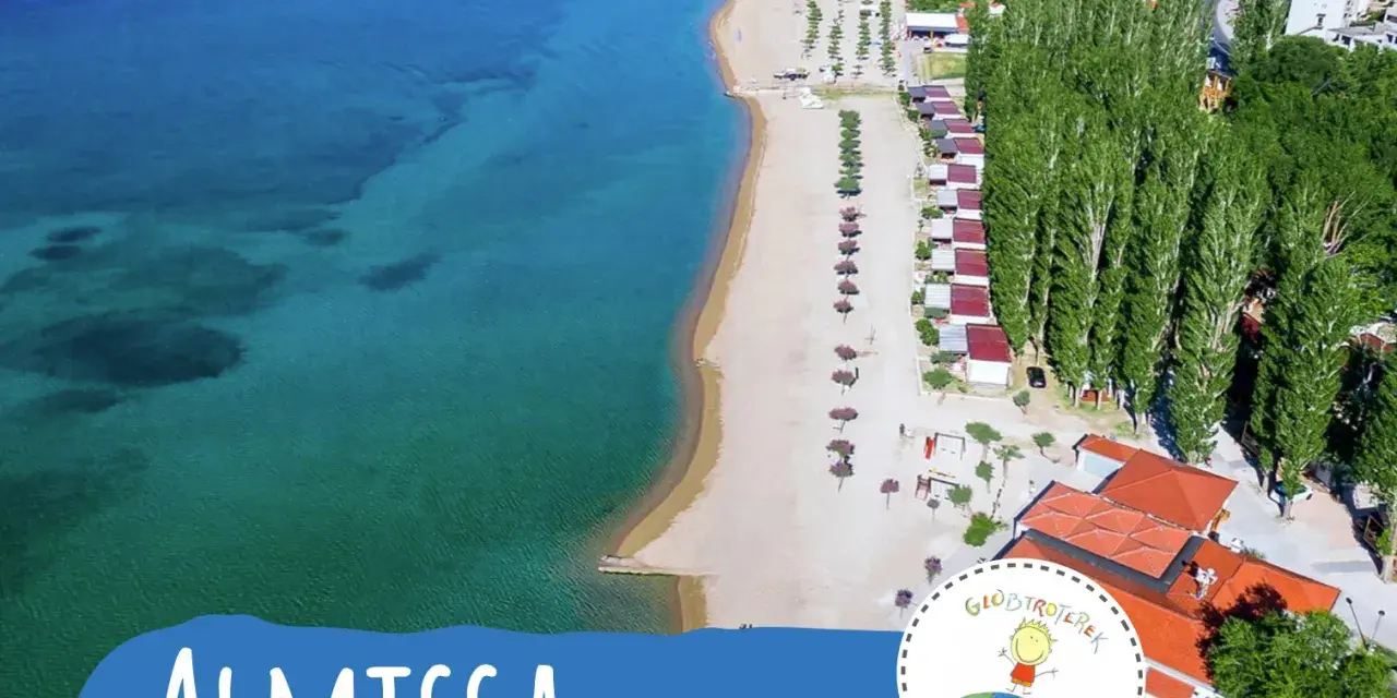 Widok z lotu ptaka na plażę i kemping Almissa (dawniej Galeb) w Chorwacji. Turkusowe morze, piaszczysta plaża, rzędy domków i wysokie drzewa.