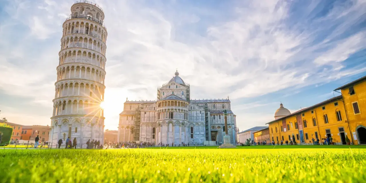 Torre di Pisa e Duomo, tra i più bei posti da visitare in Toscana, con un prato verde brillante e cielo azzurro.