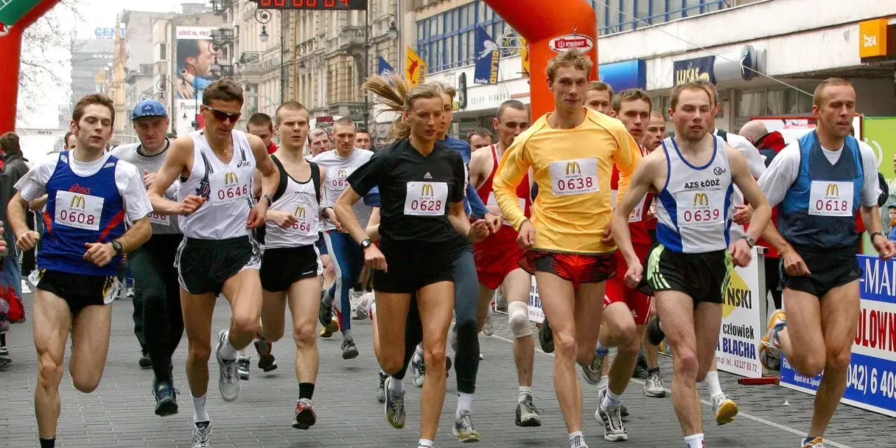 Löpare i en maratonlopp, många med nummerbrickor. En kvinna springer i mitten.