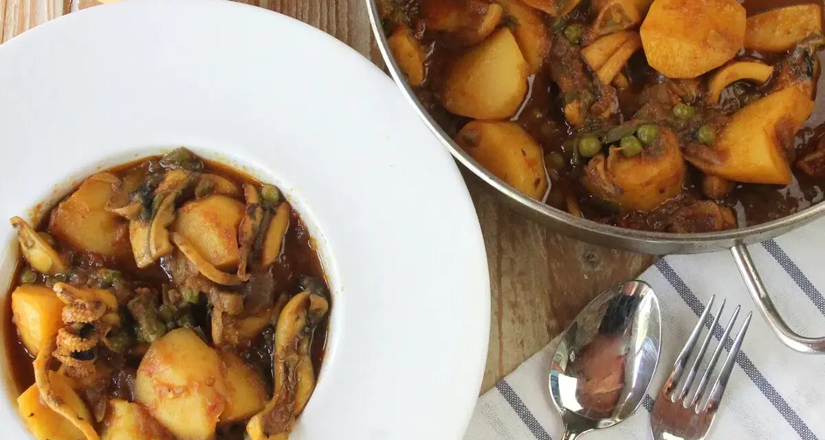 Plato de papas con choco y guisantes en salsa. Un delicioso guiso casero listo para servir.