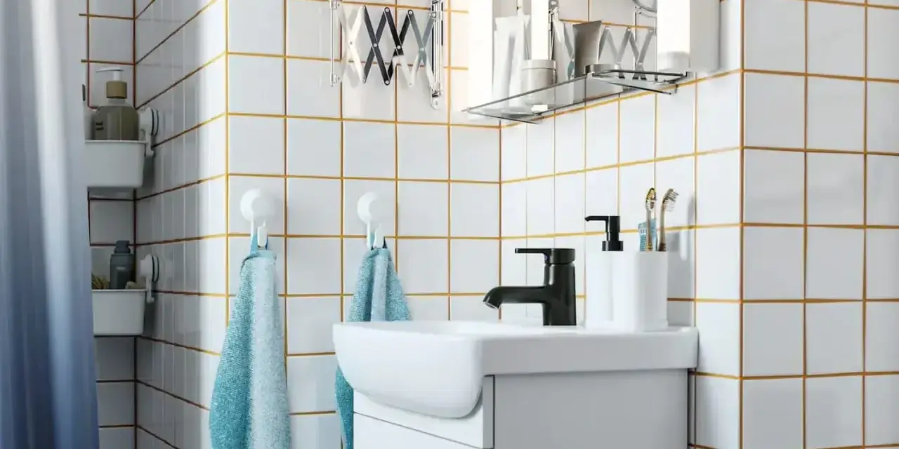 Salle de bain moderne avec carrelage blanc et joints dorés, évier, robinetterie noire et accessoires. Idéal pour un plancher chauffant avec un joint de 2mm.