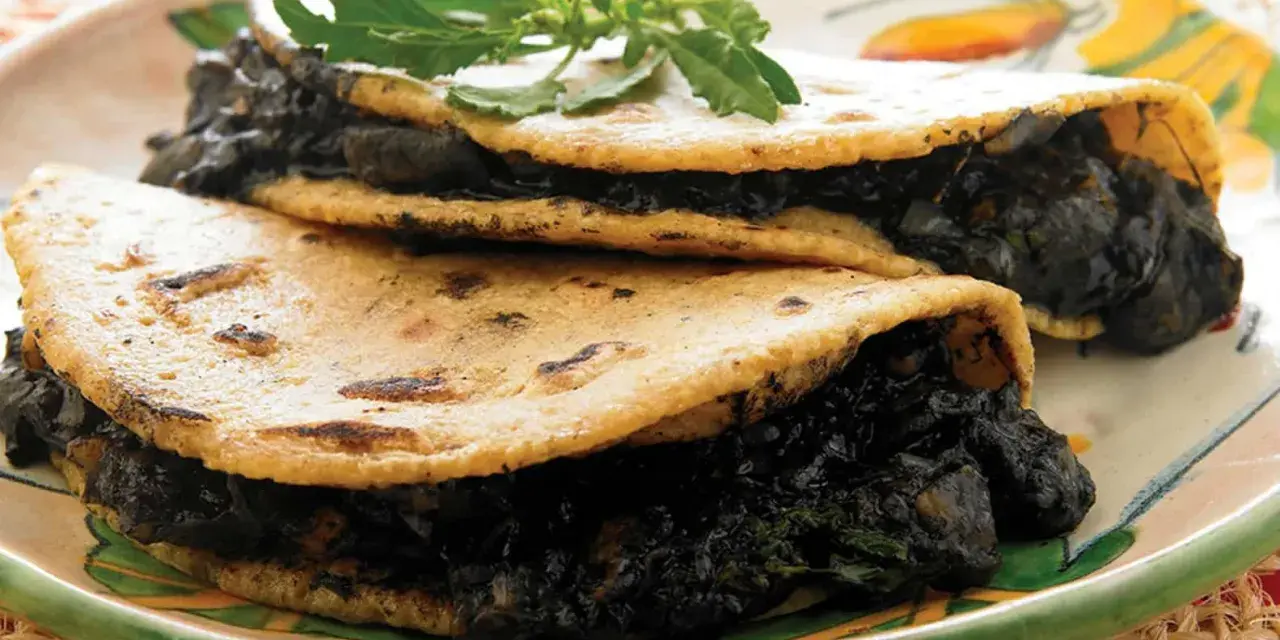 Dos tortillas de maíz rellenas de quelites, un platillo que evoca lo que comían los aztecas.