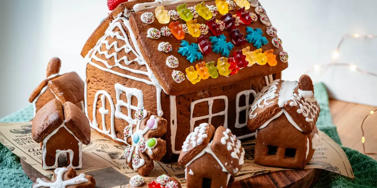 Kreative Ideen für ein Lebkuchenhaus: Ein detailreiches Lebkuchenhaus mit bunten Gummibärchen und kleinen Lebkuchenhäusern drumherum.