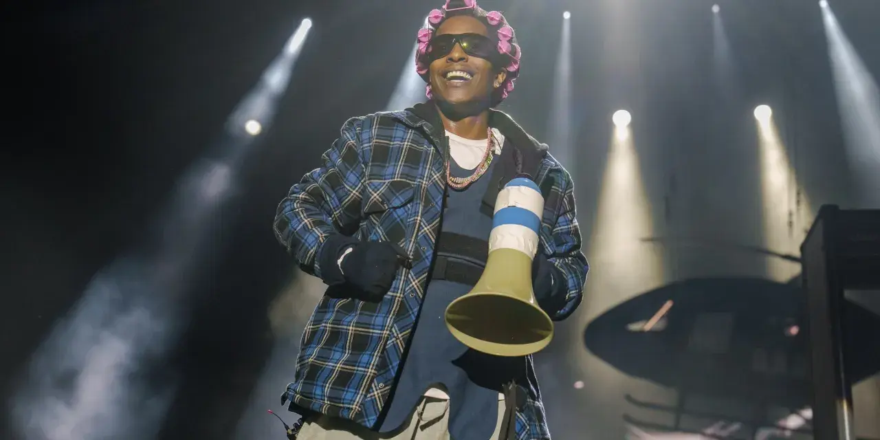 A$AP Rocky na koncercie w kręconych włosach i kratowanej koszuli, trzymający megafon.
