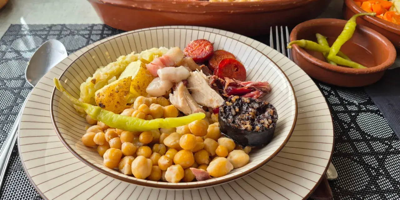Plato de cocido con garbanzos, patatas, chorizo, morcilla y pimientos.