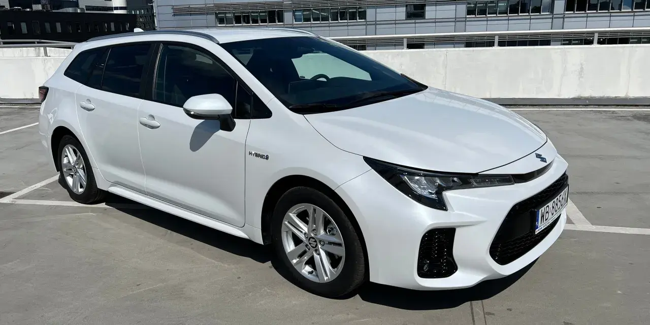 Biały Suzuki Swace Hybrid na parkingu. Elegancki kombi z nowoczesnym designem, gotowy na każdą podróż.