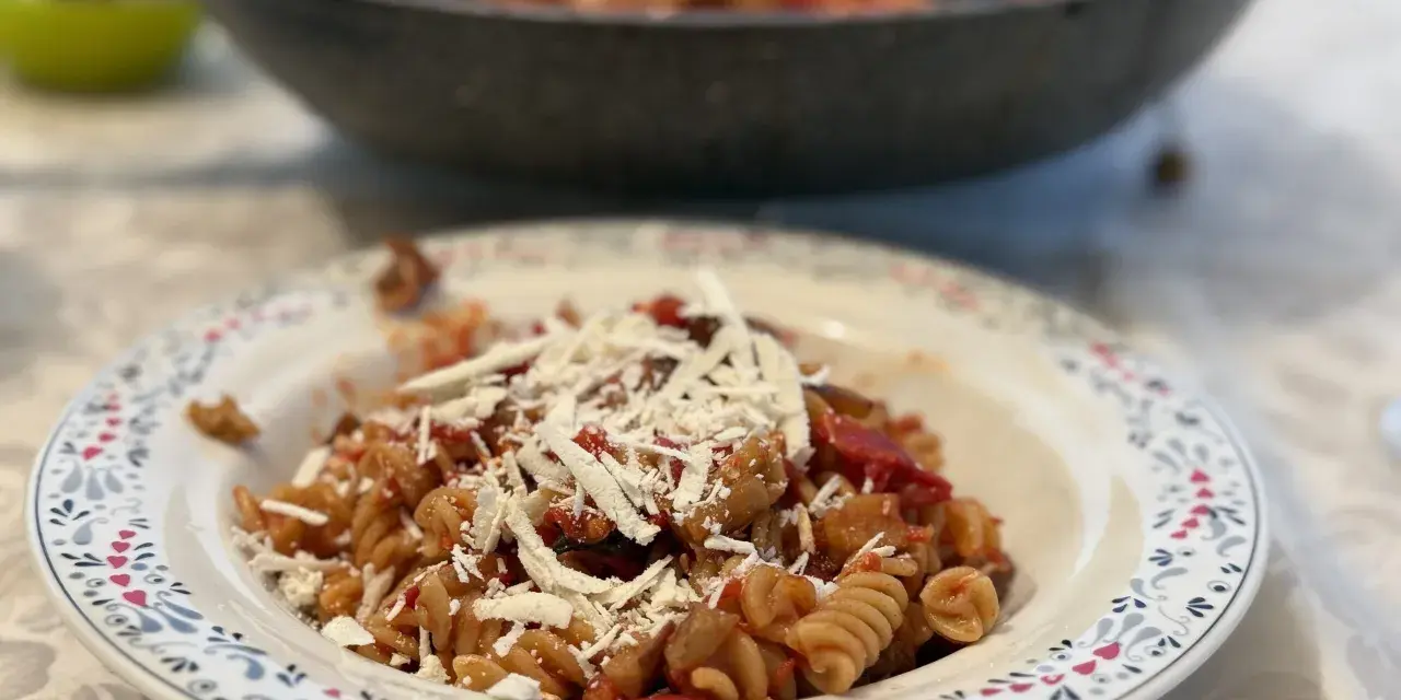 Plato de pasta alla norma con fusilli, berenjena, tomate y queso rallado, listo para disfrutar.