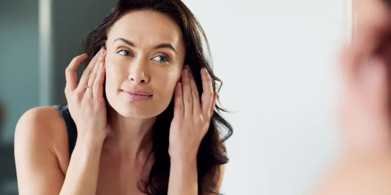 Mujer se toca la cara, preocupada por una posible cara hinchada.