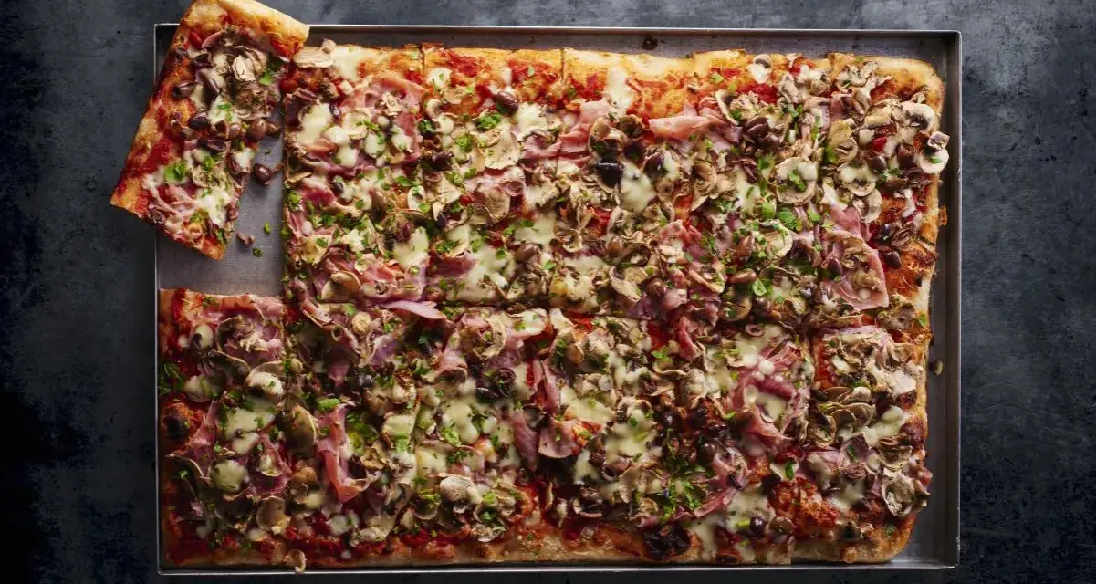 Pyszna pizza domowa przepis na blachę z szynką, pieczarkami i oliwkami. Idealna na rodzinne spotkanie.