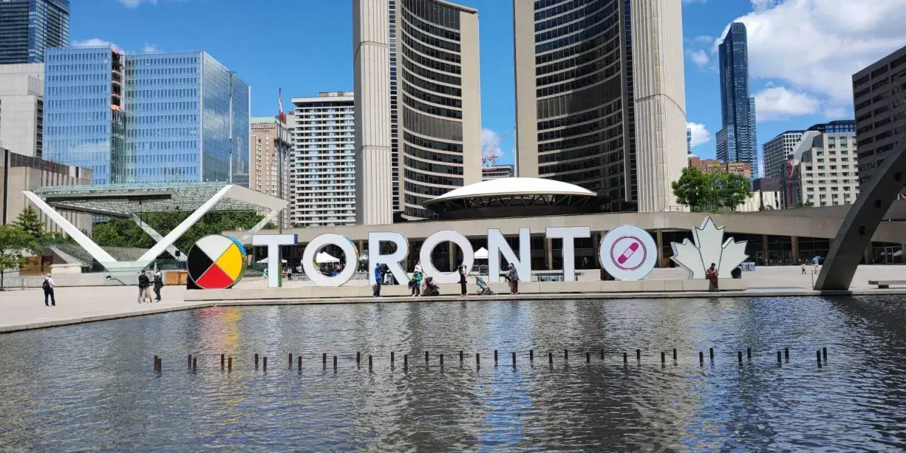 Toronto co zobaczyć: wielki napis TORONTO przed ratuszem miejskim, z fontanną i nowoczesnymi budynkami w tle.