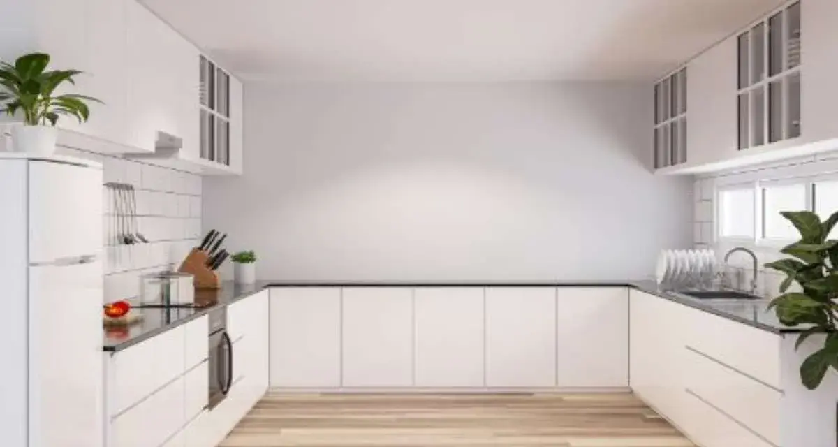 Cucina moderna con mobili bianchi e pavimento in legno. Idee per come riempire una parete vuota in cucina con mensole o quadri.