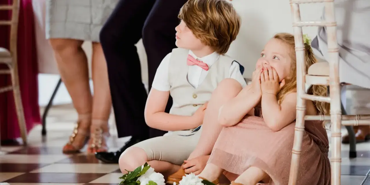 Dzieci na weselu siedzą na podłodze. Jakie są zasady zapraszania dzieci na wesele? Jak to ująć w zaproszeniu?