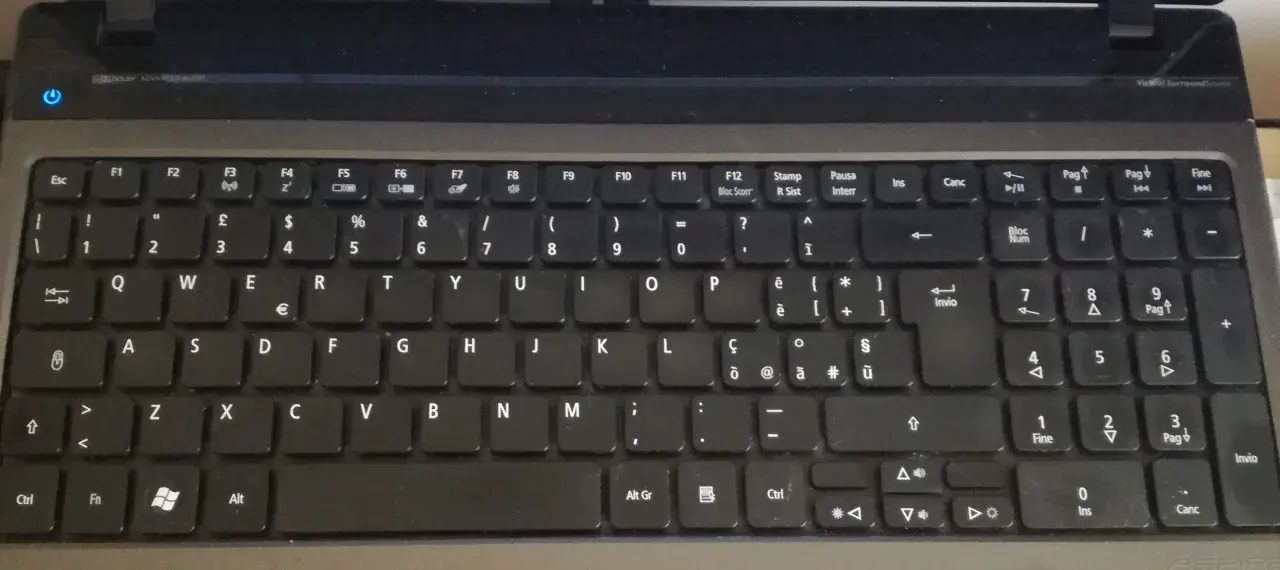 Klawiatura laptopa z włoskim układem klawiatury. Widoczne klawisze z literami, cyframi i symbolami, w tym € i accented vowels.