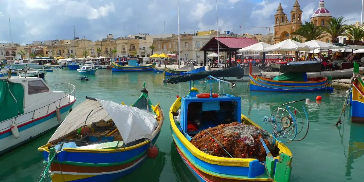 Kolorowe łodzie rybackie w porcie na Malcie, gdzie można poczuć klimat i zobaczyć, jak wygląda malta waluta w codziennym życiu.