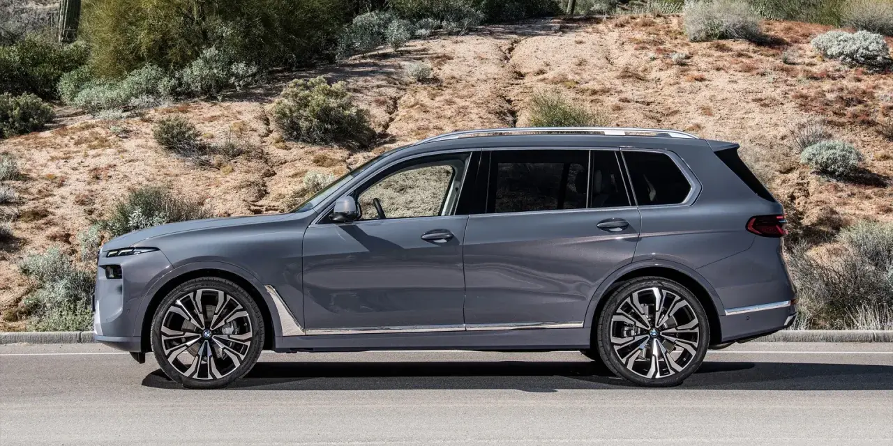 Szary BMW X9 na tle pustynnego krajobrazu. Elegancki SUV z chromowanymi detalami i masywnymi felgami.