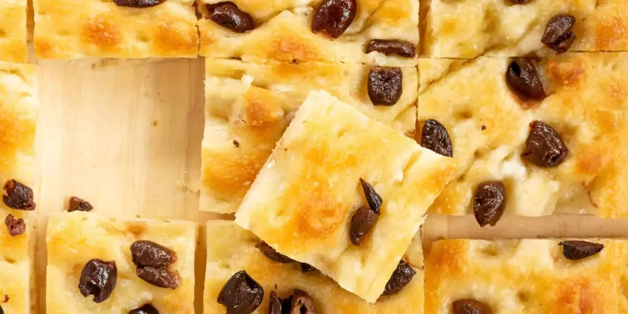 Goldbraune Focaccia mit Oliven, perfekt nach dem original focaccia rezept. Ein Stück ist leicht angehoben.