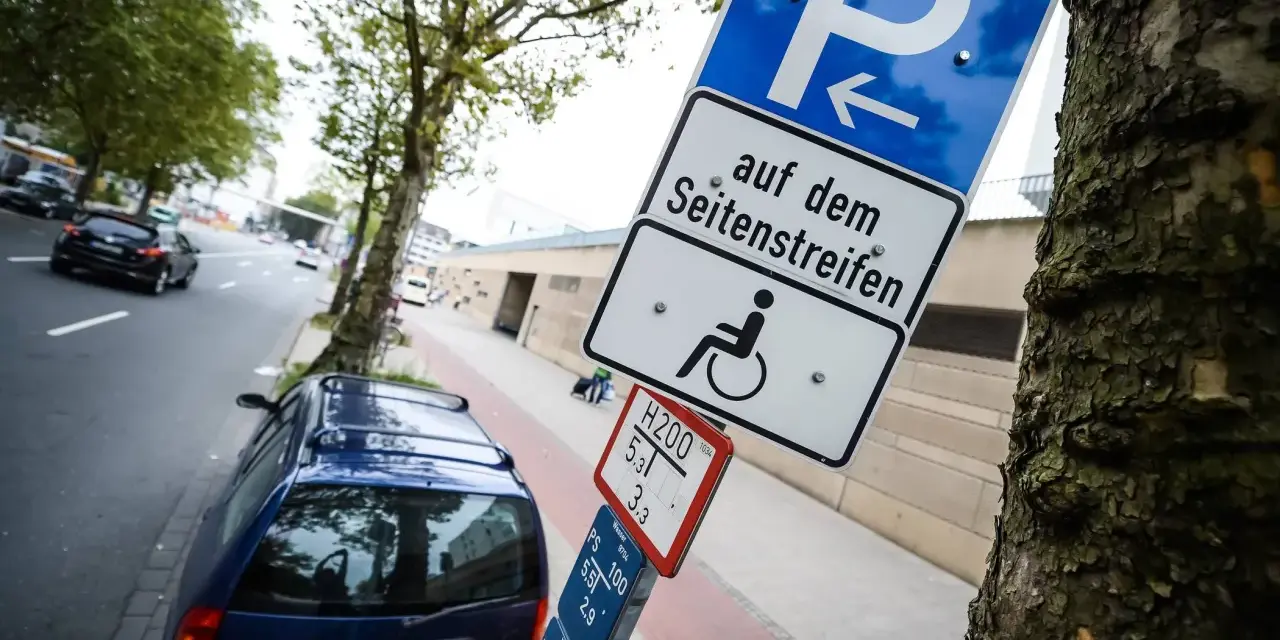 Schild für Behindertenparkplatz auf dem Seitenstreifen. Falschparken wird mit einer hohen Strafe geahndet.
