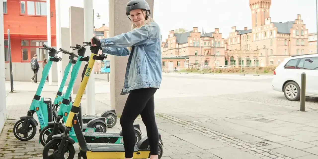 Tjej med hjälm redo att köra elsparkcykel. Tänk på elsparkcykel regler för en trygg resa.
