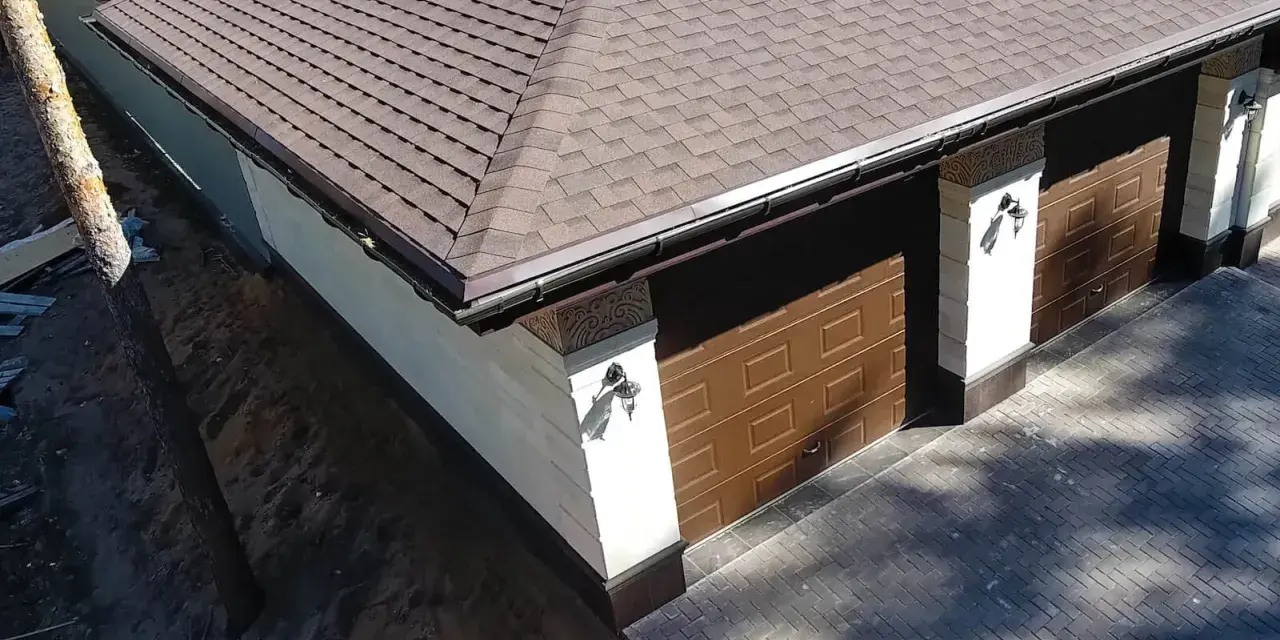 Nowy dach papa na garażu z brązowymi drzwiami i ozdobnymi słupkami.