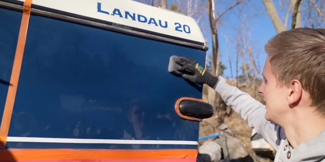 Man applicerar keramisk lackskyddsbehandling på en blå båt med texten "LANDAU 20".