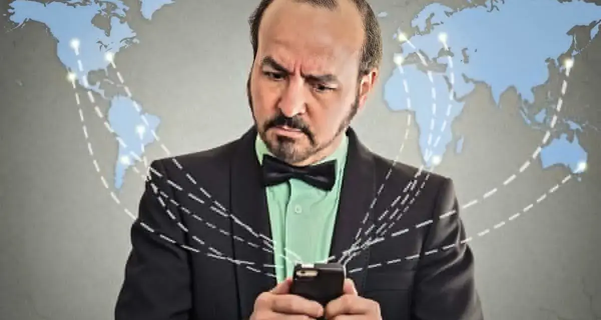 Mężczyzna w garniturze z telefonem, zastanawia się, co to roaming. Mapa świata z połączeniami sugeruje globalną sieć.