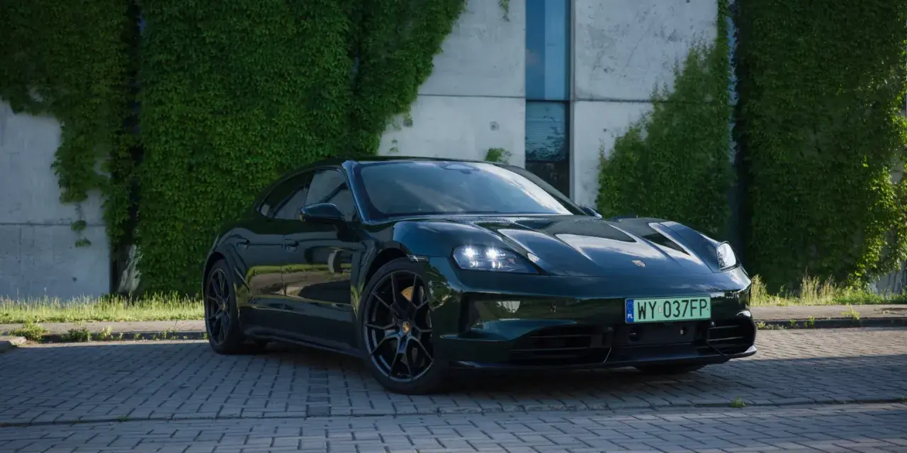 Elegancki, ciemnozielony Porsche Taycan na tle zielonej ściany z bluszczu. Sprawdź aktualną porsche taycan cena i możliwości tego elektrycznego cudu.