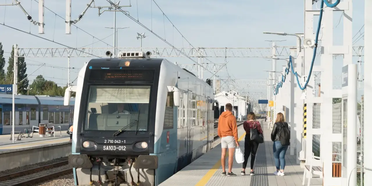Pociąg na stacji z pasażerami czekającymi na peronie.