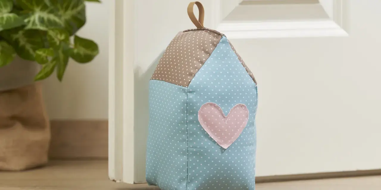 Un cale porte en tissu gratuit en forme de maison, avec un cœur rose. Parfait pour un **patron cale porte en tissu gratuit**.