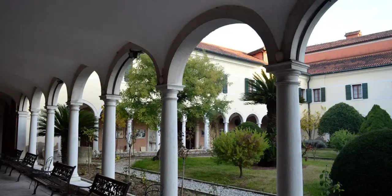 Portico con archi e colonne bianche, panchine e un giardino interno. Per sapere isola degli armeni come arrivare, visita questo luogo tranquillo.
