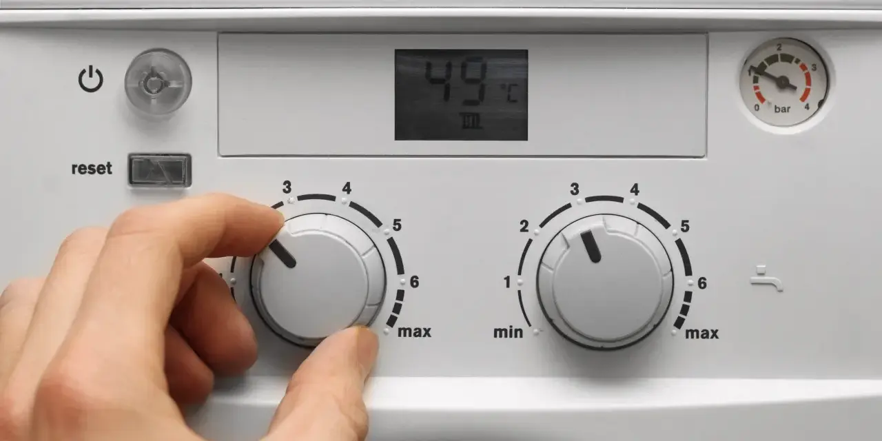 Mano che regola la caldaia spenta senza corrente. Il display mostra 49°C.